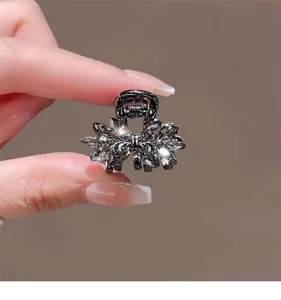 Gros-plan de petite pince à cheveux nœud en cristal et strass noirs pour frange élégante.