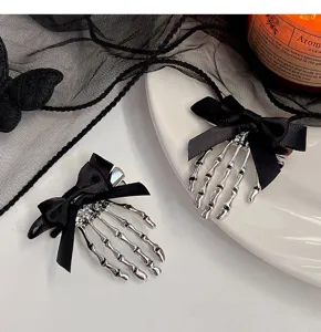 Pince à cheveux main squelette gothique avec noeud noir, accessoire Halloween détail.
