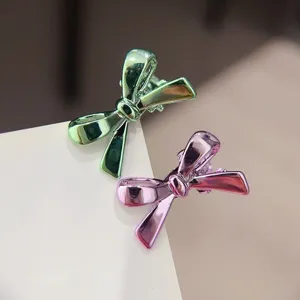 Detaillierte Nahaufnahme glänzender Metall Schleifen Haarklammern in Grün und Rosa für das Styling.