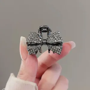 Détail de pince à cheveux nœud strass, accessoire scintillant pour coiffure élégante.
