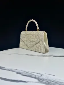 Detailed close-up of the elegant pearl and rhinestone encrusted evening bag handle and body.