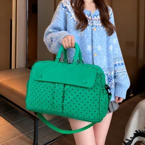 Detailed view of the large capacity polka dot travel bag, showing durable green fabric and design.