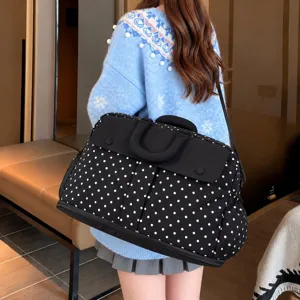 Detailed view of large black polka dot travel duffel bag with shoulder strap and carry handles.