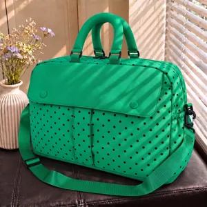 Green polka dot travel duffel bag with large capacity, dual handles, and shoulder strap.