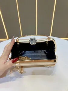 Close-up detail of luxury gold evening clutch bag with crystal flower clasp and pearl tassel.