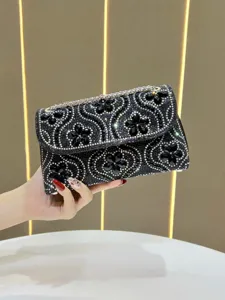 Close-up detail of luxury black rhinestone evening clutch bag with sparkling crystal design chain.