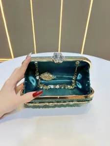 Detail view of a luxury green glitter evening clutch with sparkling crystal clasp and chain.