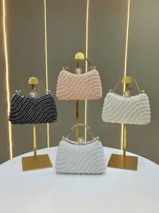 Elegant pearl beaded evening handbag featuring rhinestone details and gold handle, close-up.