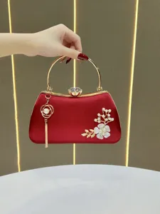 Elegant red satin evening clutch bag featuring a gold metal handle, pearl flower and chic tassel.