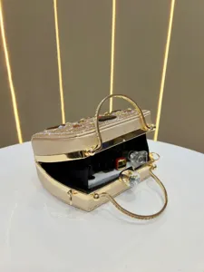 Élégante pochette de soirée dorée en strass avec poignée métallique et fermoir cristal.