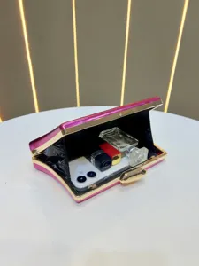 Detail view of pink metallic evening clutch bag with gold hardware and phone inside.