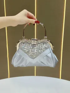 Detail shot of silver rhinestone evening bag with elegant crystal details and metallic gold handle.