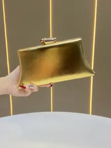 Detail of elegant metallic gold evening clutch bag with glossy finish and secure metal clasp.