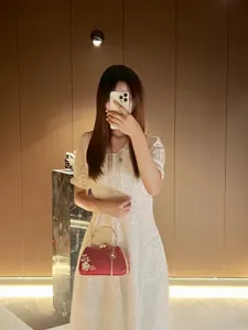 Exquisite red satin evening clutch detail, featuring pearl floral accent and elegant tassel.