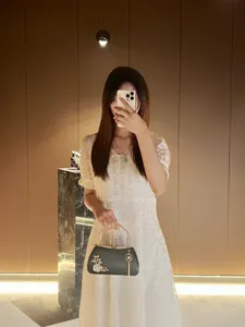 Detailed view of the black evening clutch bag with pearl floral decor, elegant tassel pendant.