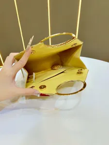 Vista dettagliata della borsa da sera gialla con manici circolari in metallo dorato.