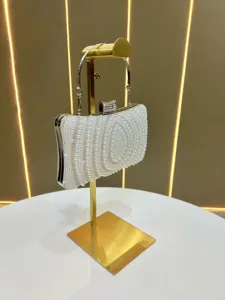 Detailed view of the elegant pearl evening clutch bag displayed on stand, highlighting texture.