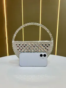 Dettaglio borsa da sera a mezzaluna in strass scintillanti con manico ad anello in cristallo.
