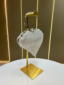 Detailed close-up of a sparkling crystal heart evening bag displayed on a modern gold stand.
