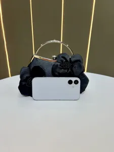 Détail de pochette de soirée en satin noir avec décoration florale et poignée anneau métal.