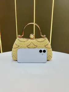 Close-up detail of luxury pearl rhinestone evening clutch bag with gold handle and clasp.