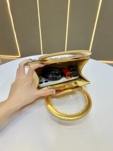 Detail shot of a glamorous gold rhinestone evening bag showing interior capacity and storage.