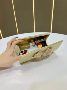 Gold rhinestone bow evening clutch bag, elegant accessory for parties and banquets.