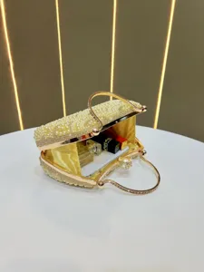 Detailed view of luxury gold pearl rhinestone evening clutch bag with elegant crystal handle.