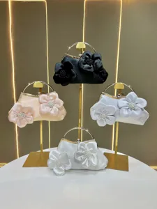 Élégant sac de soirée en satin avec design de fleurs en perles et poignée en anneau métallique.