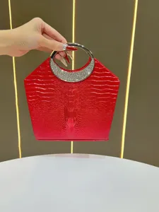 Dettaglio borsa da sera rossa coccodrillo con manico rotondo in strass per feste formali.