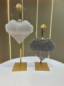 Detailed view of glittering crystal heart evening clutch bag with metal handle and tassel.