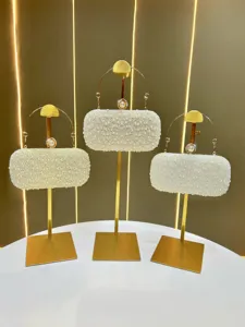 Detailed showcase of pearl evening clutch bags on gold display stands, highlighting craftsmanship.