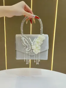 Close-up view of a luxury grey velvet evening handbag featuring a sparkling rhinestone butterfly.
