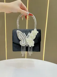 Close-up detail of a black evening handbag featuring sparkling rhinestones and butterfly decor.