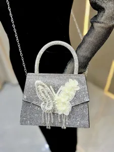 Detailaufnahme der Strass-Abendtasche, funkelnder Kristallschmetterling mit Quasten an Kette.