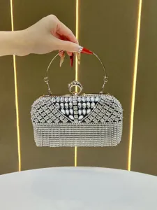 Detalle en primer plano del lujoso bolso de mano de noche con pedrería y asa metálica.