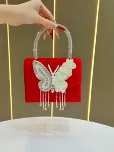 Red velvet evening bag detail featuring sparkling rhinestone handle and crystal butterfly decor.