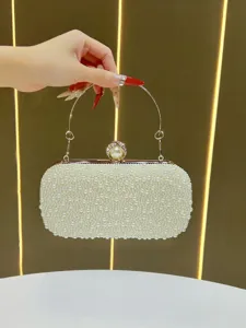 Pearl evening clutch bag detail, elegant metal handle, luxury bridal handbag close-up.