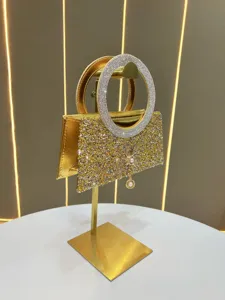 Exquisite gold rhinestone evening bag detail, sparkling round handle and pearl pendant.