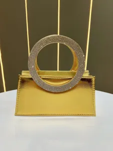 Golden metallic evening bag with stunning rhinestone circular handle for elegant ladies.