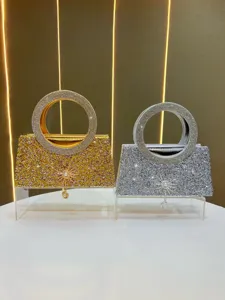 Close-up detail of the glittering evening handbag featuring a round handle and sun pendant.