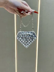Close-up view of the sparkling rhinestone diamond-shaped clutch bag held by hand, shining brilliantly.