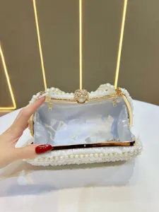 Close-up detail of the elegant white pearl and lace evening clutch bag clasp opening.