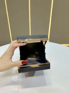 Detail view of sparkly evening clutch bag, open structure with metallic frame and chain strap.