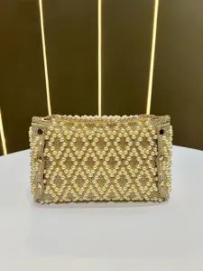 Detailed close-up of pearl rhinestone evening clutch bag with elegant gold chain strap.