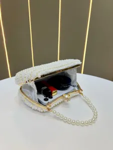 White pearl evening clutch bag detail view, elegant beaded handle and gold hardware.