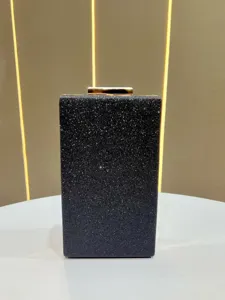 Black glitter evening clutch bag detail, showing sparkling surface and gold clasp.