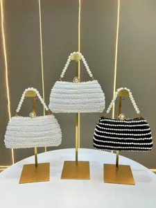 Detailed shot of elegant pearl beaded evening handbag with metal clasp and pearl handle.