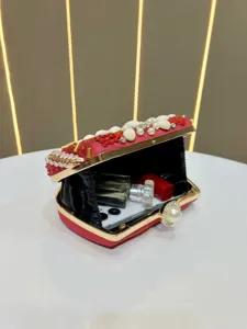 Detailaufnahme einer roten Abendtasche mit Perlen und edlem Zubehör im eleganten Innenraum.