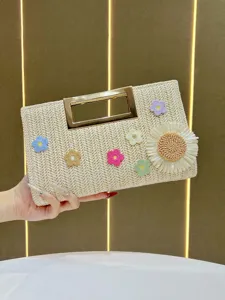 Chic straw woven clutch bag with gold metal handle and colorful crochet flower decor for summer.